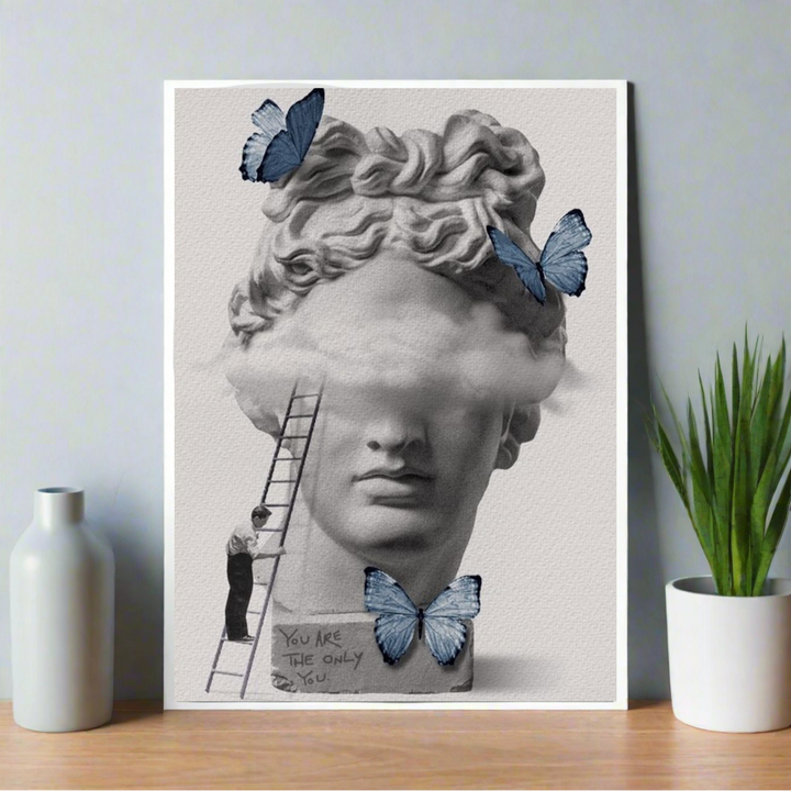 Poster showing a surreal Greek bust with clouds obscuring the eyes, blue butterflies around, and a handwritten message “You are the only you” at the base. Aesthetic Poster, Greek style poster, Hostel dorm decor ideas,Room decor, Home decor ideas, posters, Poster.